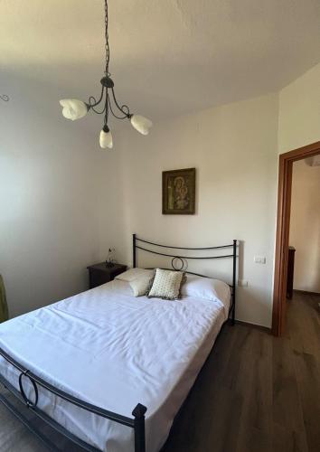 a bedroom with a bed with white sheets and a chandelier at SOFT ALBA apartment in Sasso dʼOmbrone