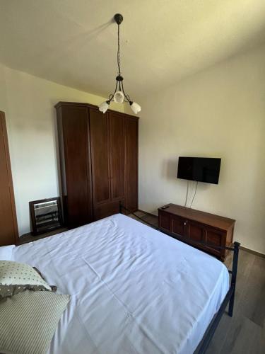 a bedroom with a white bed and a tv at SOFT ALBA apartment in Sasso dʼOmbrone