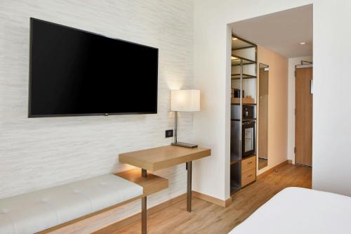 a bedroom with a desk and a tv on a wall at AC Hotel by Marriott Fort Lauderdale Beach in Fort Lauderdale
