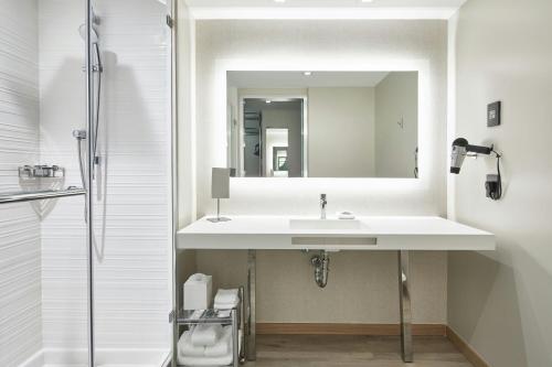 a white bathroom with a sink and a mirror at AC Hotel by Marriott Fort Lauderdale Beach in Fort Lauderdale