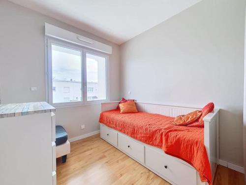 une chambre avec un lit avec des draps orange et une fenêtre dans l'établissement Appartement 3 pièces ROYAN - Centre Ville, à Royan