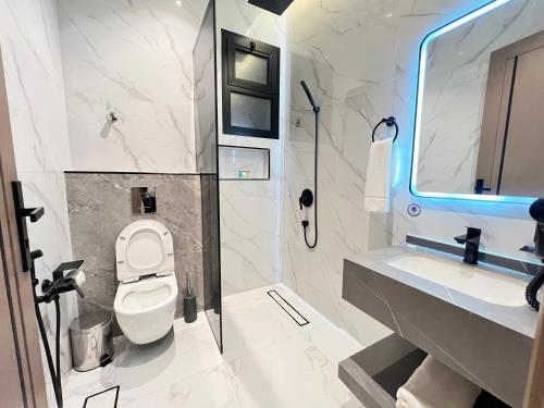 a bathroom with a toilet and a sink and a mirror at مهد إن شقق مخدومة جديدة Mahd Inn Hotel in Riyadh
