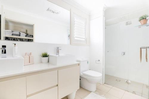 a white bathroom with a toilet and a sink at Blue Haven Retreat - Jordan Springs in Kingswood