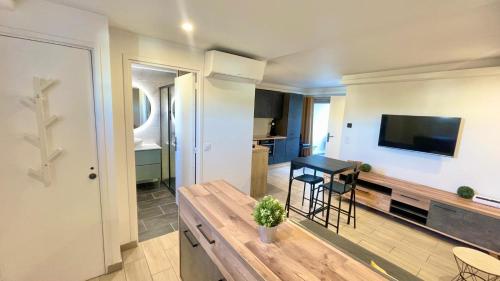 a living room with a table and a tv on a wall at T2 moderne avec piscine, tennis et garage in Cagnes-sur-Mer