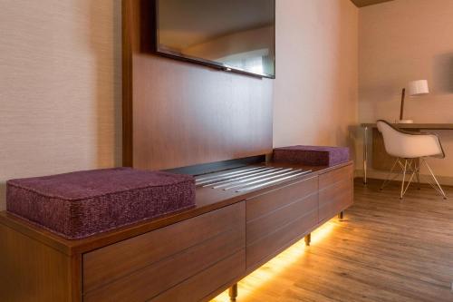 a living room with a tv on top of a cabinet at The Del Monte Lodge Renaissance Rochester Hotel & Spa in Rochester