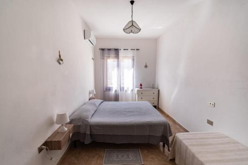 a white bedroom with a bed and a window at Ale house experience in Riola Sardo
