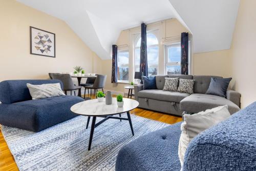 a living room with blue couches and a table at Lovely 4-BR Home In Leyton - Sleeps 14, Near Tube, Arcade, 100inchTV in London