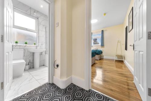a hallway with a bathroom with a sink and a toilet at Lovely 4-BR Home In Leyton - Sleeps 14, Near Tube, Arcade, 100inchTV in London