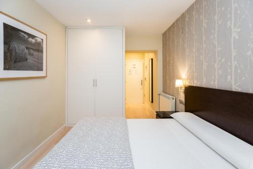 1 dormitorio con cama y pared en Pensión Altair, en San Sebastián