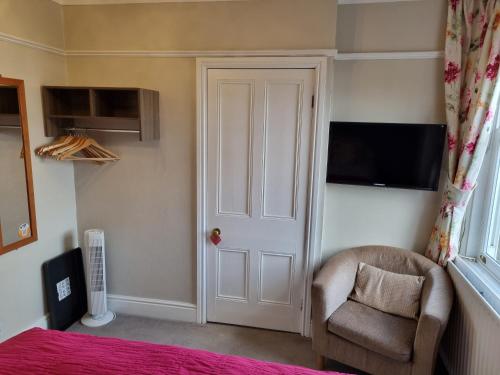 a bedroom with a bed and a chair and a television at Montfort Cottage Guest House in Windermere