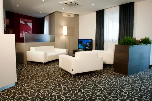 a lobby with couches and a tv in a building at Hotel Gardenia in Romano Canavese