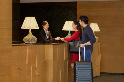 a man and a woman shaking hands at a counter at Renaissance Johor Bahru Hotel in Johor Bahru