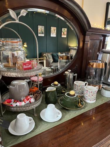a table with dishes and cups and a mirror at Dinmont Cottage in Dalston