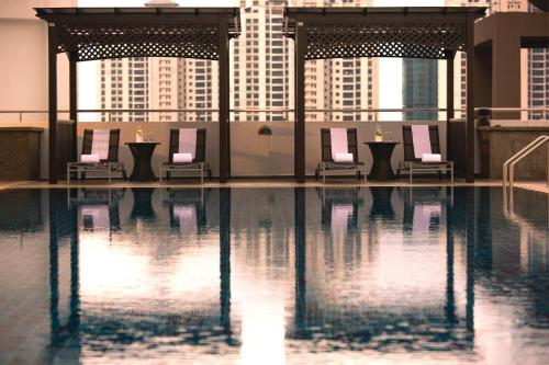 a pool with a row of chairs in a building at Renaissance Johor Bahru Hotel in Johor Bahru