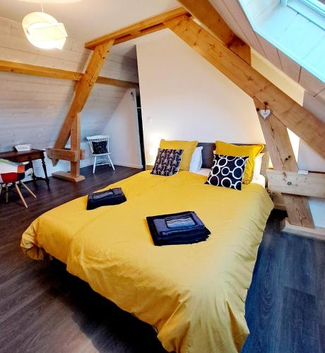 - une chambre mansardée avec un grand lit jaune dans l'établissement La maison au bout du chemin, à Poey-dʼOloron