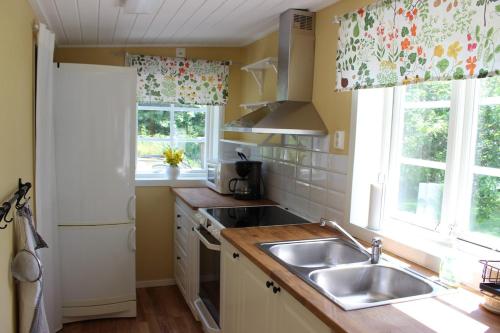 a kitchen with a sink and two windows at Cozy cottage close to both nature and city in Lysekil