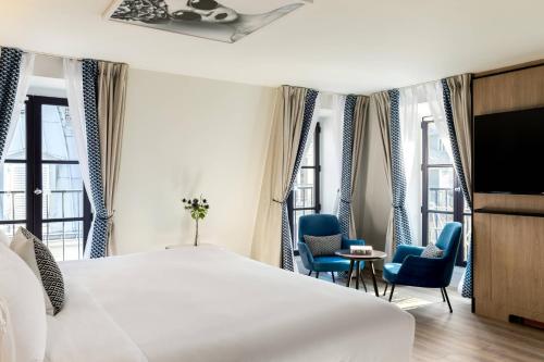a bedroom with a large white bed and two blue chairs at Renaissance Paris Vendome Hotel in Paris