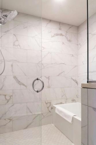 a bathroom with a shower with a tub and a sink at Hotel Saint Louis, Autograph Collection in Saint Louis