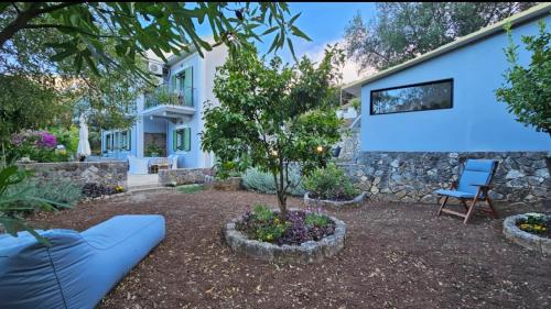 a house with a blue chair and a tree in a yard at The Blooming House in Makriótika