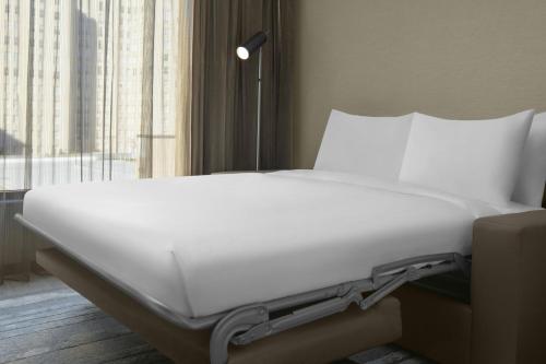 a white bed in a room with a window at AC Hotel by Marriott St Louis Central West End in Saint Louis