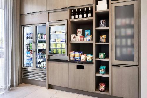 a kitchen with a refrigerator and shelves with food at AC Hotel by Marriott St Louis Chesterfield in Chesterfield