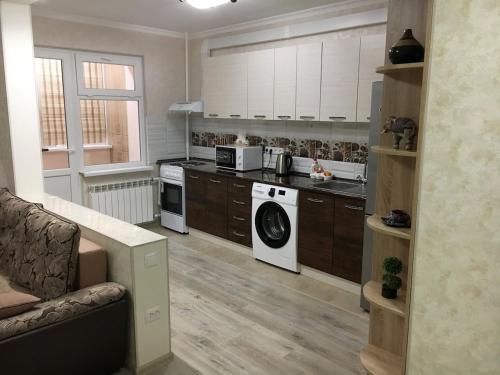 a kitchen with white appliances and a couch in a room at Apartment for rent number 1 in Aktau