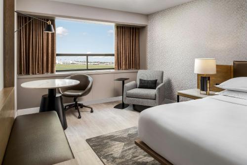 a hotel room with a bed and a desk and chair at Sheraton Montreal Airport Hotel in Dorval
