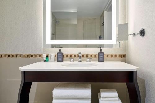 a bathroom with a sink and a mirror and towels at Sheraton Montreal Airport Hotel in Dorval