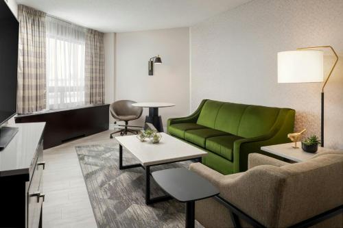 a living room with a green couch and a table at Sheraton Montreal Airport Hotel in Dorval