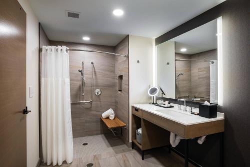 a bathroom with a sink and a shower with a shower curtain at Elliot Park Hotel, Autograph Collection in Minneapolis