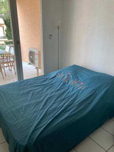un lit avec une feuille bleue au-dessus dans l'établissement Appartement front de mer Cavalaire, à Cavalaire-sur-Mer