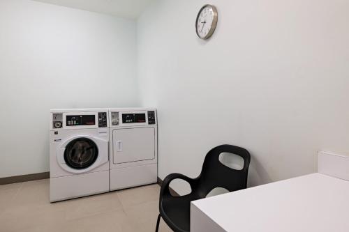 a washing machine in a room with a table and a chair at Aloft San Antonio UTSA Area in San Antonio