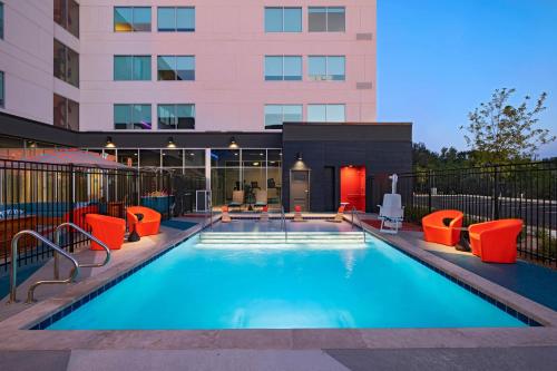 a swimming pool with orange chairs and a building at Aloft San Antonio UTSA Area in San Antonio