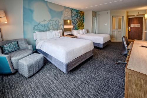 a hotel room with two beds and a chair at Courtyard by Marriott Dulles Airport Herndon in Herndon