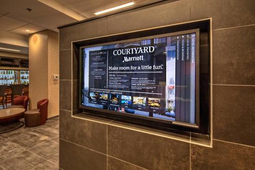 a large flat screen tv on a wall in a restaurant at Courtyard by Marriott Dulles Airport Herndon in Herndon