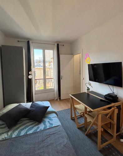 Cette chambre comprend un lit, une table et une télévision. dans l'établissement Bright studio, à Paris