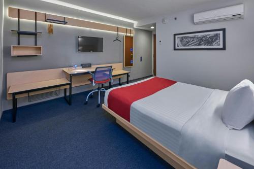 a hotel room with a bed and a desk and a computer at City Express by Marriott Ciudad de México Plaza Central in Mexico City