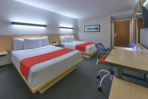 a hotel room with two beds and a desk at City Express by Marriott Ciudad de México Plaza Central in Mexico City