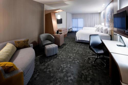 a hotel room with two beds and a couch at Courtyard by Marriott Houston North/Shenandoah in The Woodlands