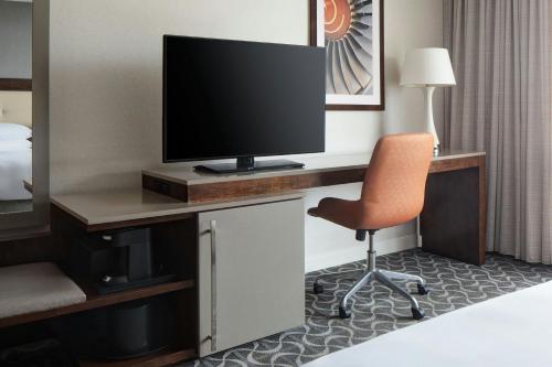 a room with a desk with a television and a chair at Marriott St. Louis Airport in Edmundson