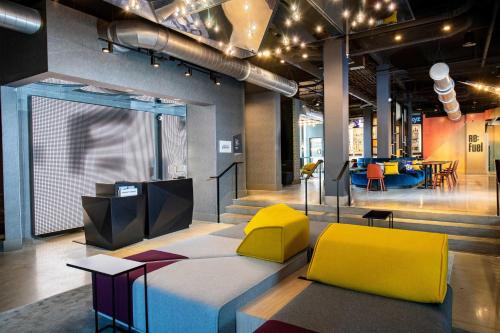 a room with a bed and two yellow chairs at Aloft Savannah Downtown Historic District in Savannah