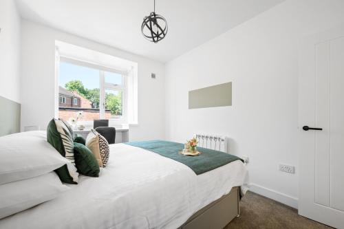 a white bedroom with a bed with a window at Ideal Lodgings In Urmston in Urmston