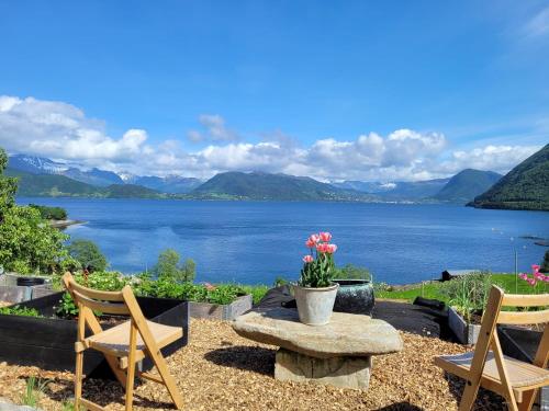 two chairs and a table with a view of a lake at Irenegarden - Fjord view holiday home in Lauvstad