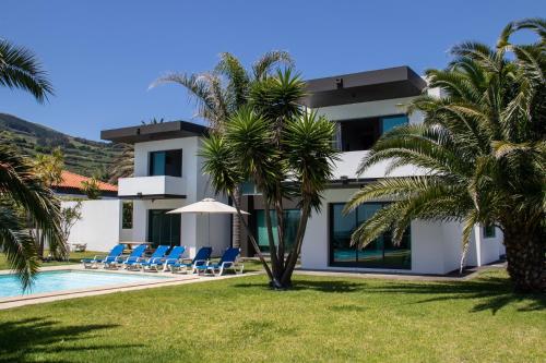 a villa with a swimming pool and palm trees at Luxury Villas in Vila Franca do Campo