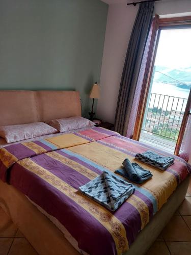 a bedroom with a bed with a large window at Casa Angela Gravedona Consiglio di Rumo in Consiglio di Rumo