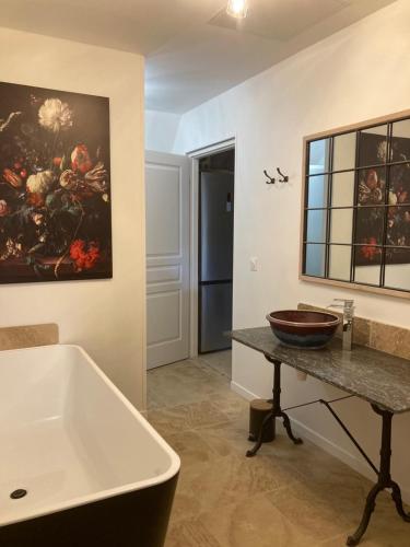 a bathroom with a tub and a painting on the wall at Le gîte du parayre in Lunac