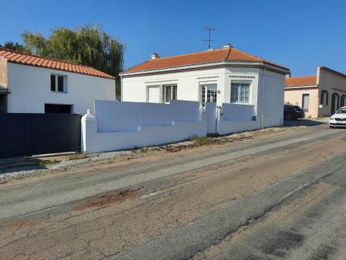 une maison blanche avec une clôture sur le côté d'une route dans l'établissement Proche Vendee La maison du Bonheur, à Fresnay-en-Retz
