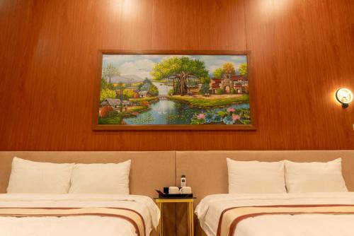 two beds in a hotel room with a painting on the wall at Sunny Garden Riverside Hotel Ninh Binh in Ninh Binh