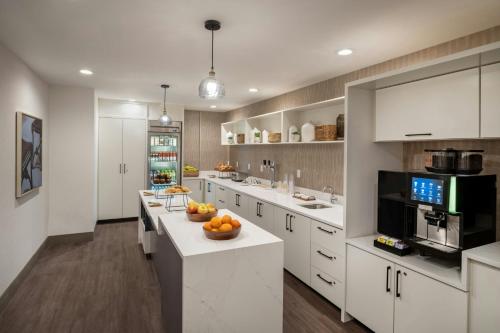 a kitchen with white cabinets and a bowl of fruit on a counter at Delta Hotels by Marriott Jacksonville Deerwood in Jacksonville