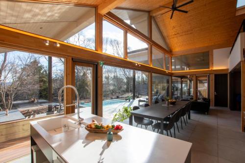 an open kitchen and dining room with large windows at Villa Metsä KARUIZAWA ヴィラメッサ軽井沢 in Karuizawa